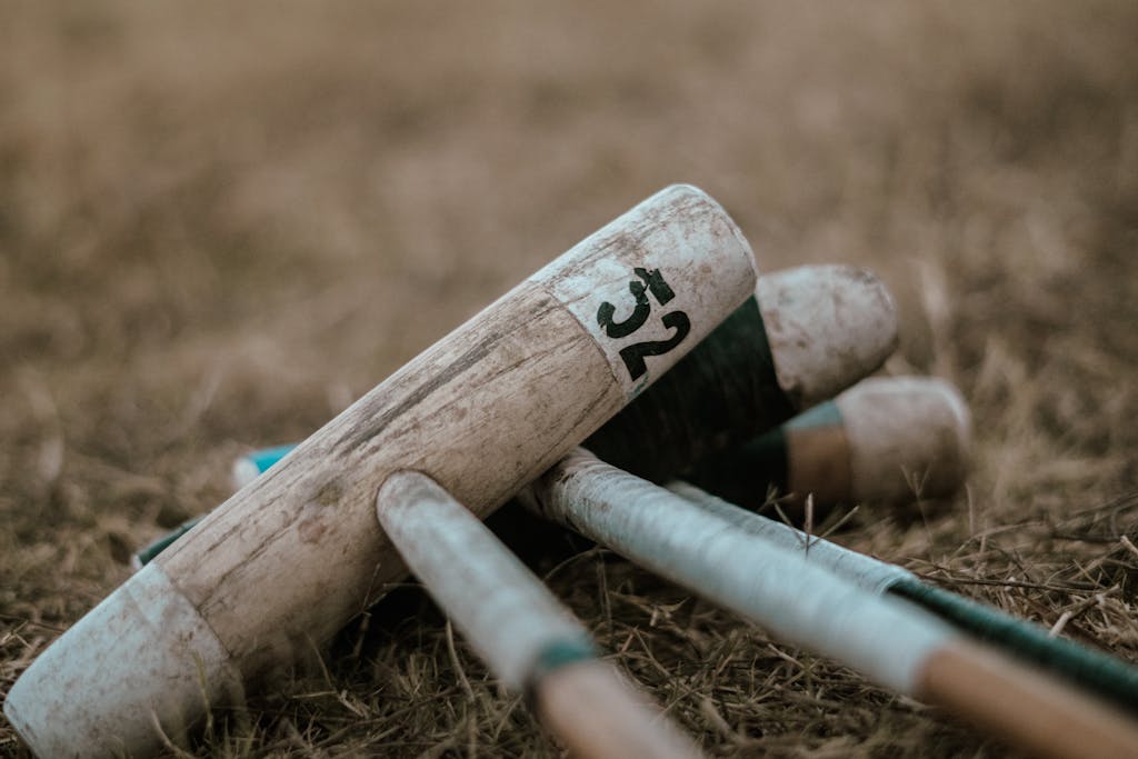 Stack of wooden croquet mallets on grass, showcasing sporting equipment.
